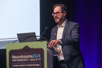 Adam Ferguson, PhD, speaking at the podium at NNS 2024