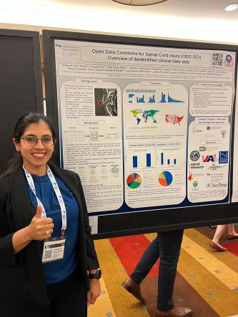 Postdoctoral scholar Prakruthi Amar Kumar, PhD, stands in front of her poster with thumbs-up